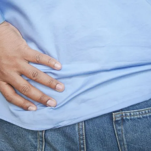 腰からお尻のあたりを押さえる男性